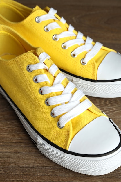 Pair of yellow sneakers on wooden background