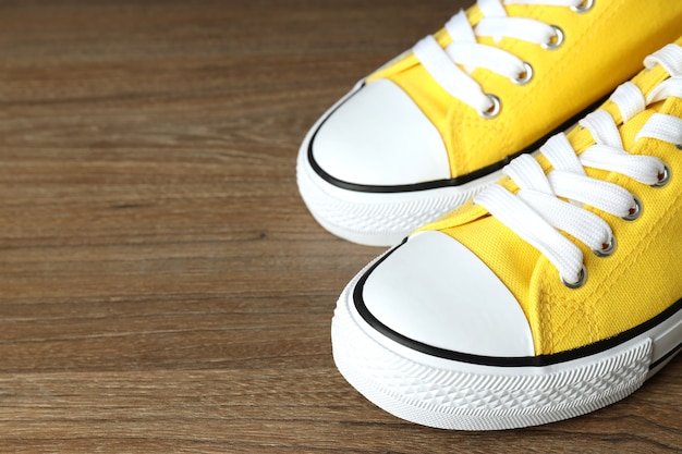 Pair of yellow sneakers on wooden background