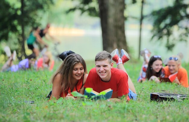 Photo pairs of students preparing for the exam lying on the grass in the park