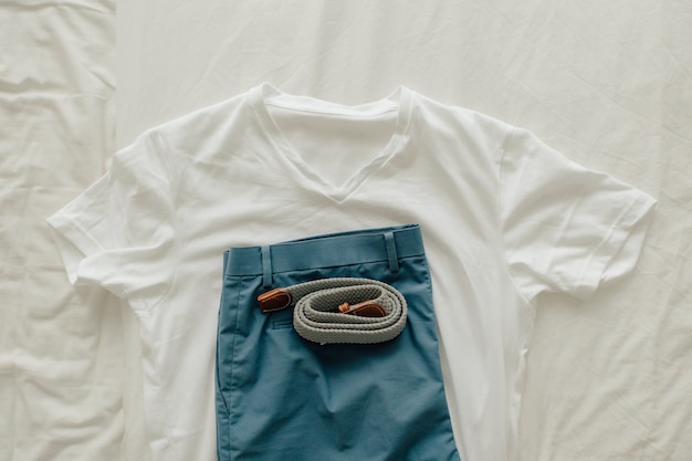 Pak kleren op het bed met een wit t-shirt blauw short en kleden riem.