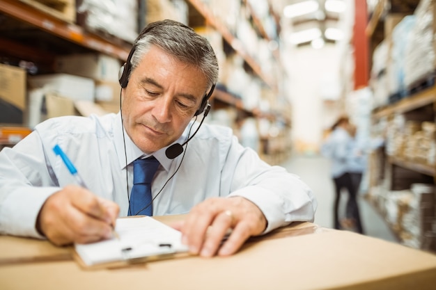 Pakhuismanager die op klembord schrijft