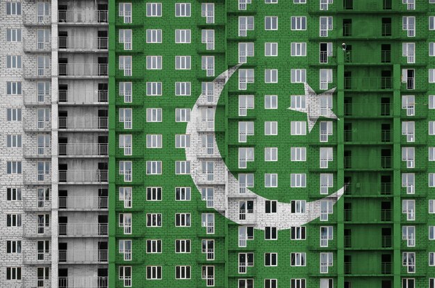 Foto bandiera pakistana raffigurata nei colori della vernice su un edificio residenziale a più piani in costruzione striscione testurizzato su sfondo di un grande muro di mattoni