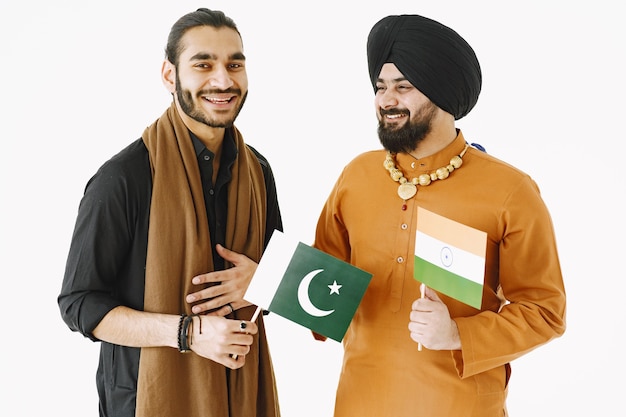 Pakistani man and Indian men in traditional clothes. The friends are talking at white background, isolated. Agremment between countries.