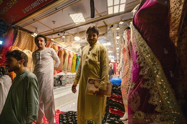페샤와르 파키스탄의 Qissa Khwani Bazaar에서 화려한 천과 드레스를 파는 파키스탄 남자