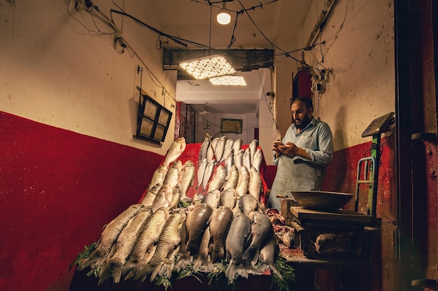 Pakistani man wearing traditional clothes selling fish on the market in Peshawar Pakistan