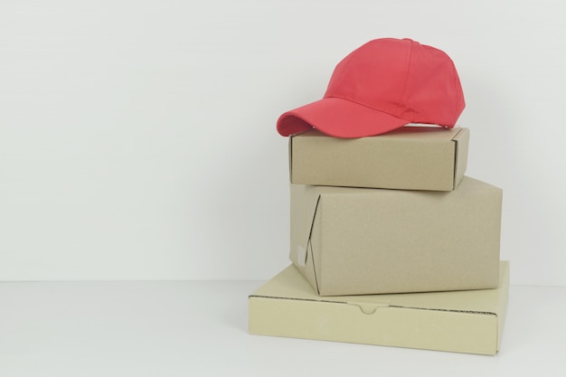 Pakket box pizzadoos met rode baseball cap op witte achtergrond kopie ruimte levering concept