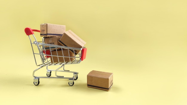 pakket in winkelwagentje op gele achtergrond Het concept van handel online winkeldelivering
