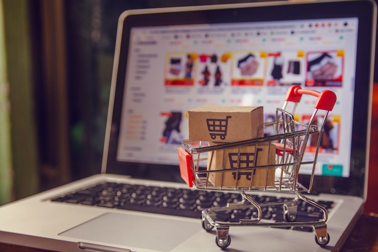 Foto pakket- of papierdozen met een winkelwagenlogo in een trolley op een laptop toetsenbord
