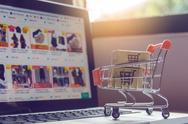 Foto pakket- of papieren dozen met een winkelwagentje-logo in een trolley op een laptoptoetsenbord.