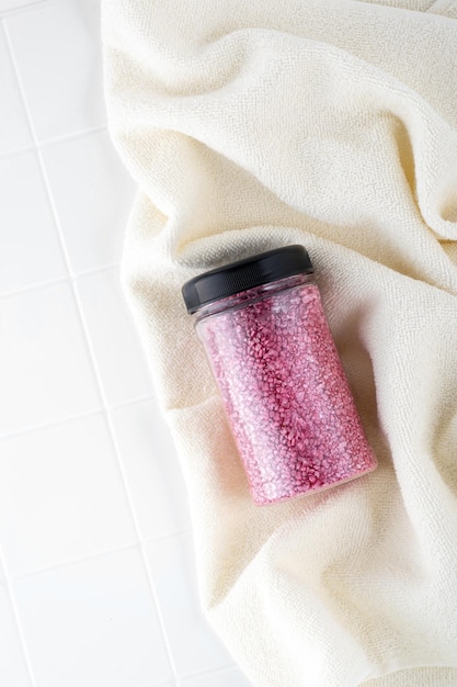 Pakket roze glanzend kristalzout op een beige badkamerhanddoek Pot met glinsterend roze zeezout voor thuisspa Idee van ontspanning, aromatherapie en zelfzorg Het effect van zeewater op haar