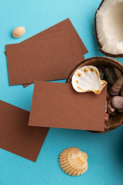 Pakpapier visitekaartje met kokos en schelpen op blauwe pastel achtergrond bovenaanzicht kopie ruimte