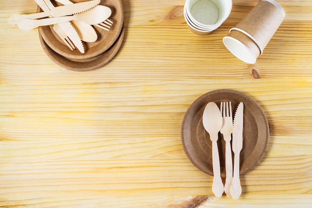 Pakpapierkoppen, platen, houten bestek op houten achtergrond