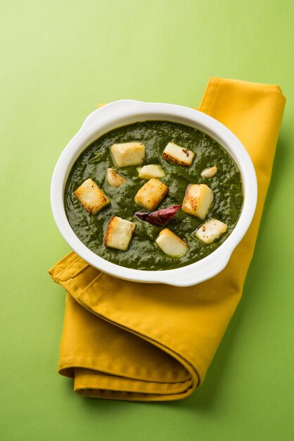 시금치와 코티지 치즈로 구성된 Palak Paneer Curry는 인기 있는 인도 건강식 점심 또는 저녁 식사 메뉴로, 분위기 있는 배경 위에 Roti 또는 Chapati와 함께 Karahi에서 제공됩니다. 선택적 초점