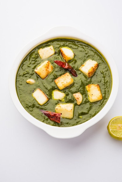 Palak Paneer Curry made up of spinach and cottage cheese, Popular Indian healthy Lunch or Dinner food menu, served in a Karahi with Roti Or Chapati over moody background. selective focus