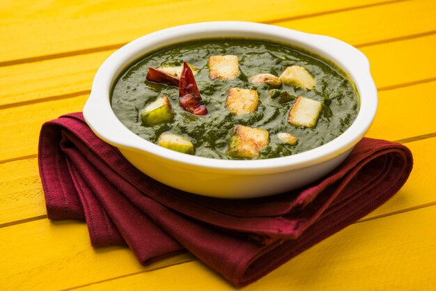 Palak Paneer Curry made up of spinach and cottage cheese, Popular Indian healthy Lunch or Dinner food menu, served in a Karahi with Roti Or Chapati over moody background. selective focus