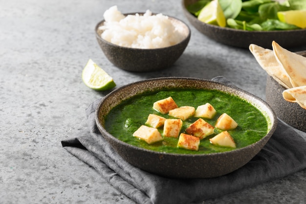 Palak Paneer served with basmati rice on a gray background. Indian vegetarian cuisine made of spinach and paneer cheese. Copy space. View from above.