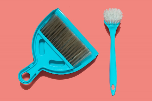 A pale blue dustpan, brush and brush for dish washing lying 