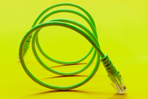 노란색 배경 근접 촬영에 DOF 커넥터가 있는 옅은 녹색 네트워크 케이블