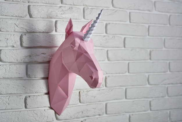 Testa di unicorno di colore rosa pallido, fatta di carta.