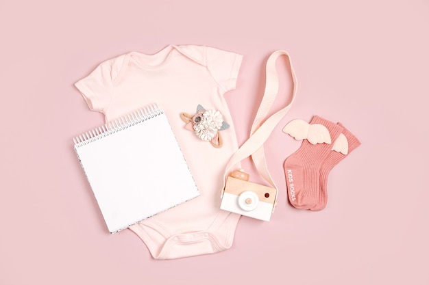 Pale pink cute baby bodysuit with mock up card. Set of kids clothes and accessories. Fashion newborn. Flat lay, top view