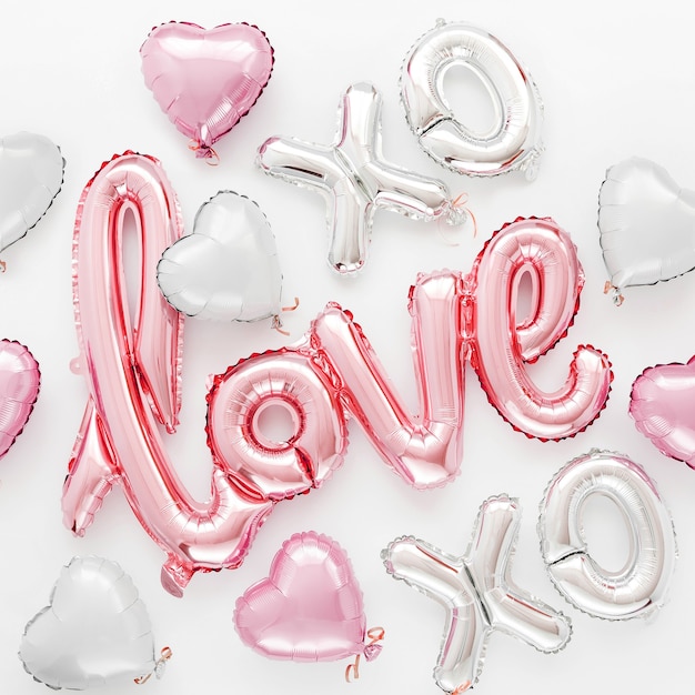 Pale pink Foil Balloons in the shape of the word "Love" with hearts on white background. Love concept. Holiday, celebration. Valentine's Day or wedding/bachelorette party decoration.