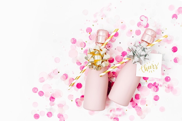 Pale Pink Mini bottles of champagne with confetti and tinsel. Flat lay. New year/Christmas celebration or wedding  concept theme. Flat lay, top view