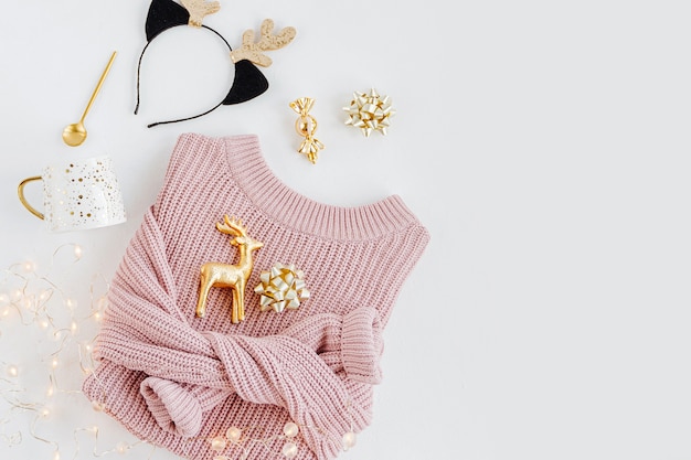 Pale pink warm sweater with Christmas decorations. Cozy Winter look. Holiday concept. Flat lay, top view.