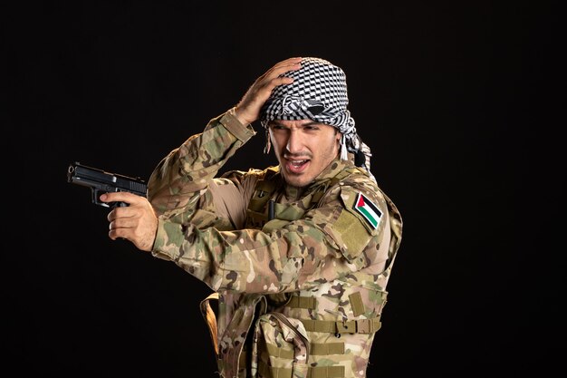 Palestinian soldier in camouflage with gun on a black wall