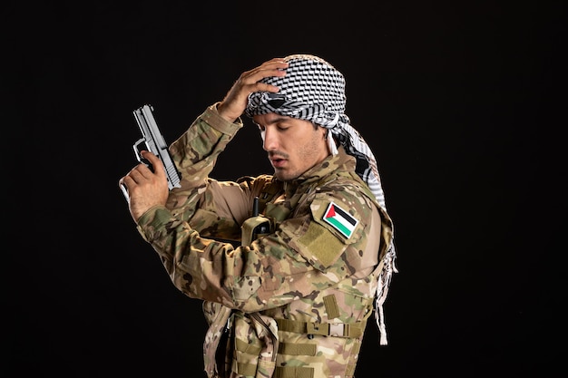 Palestinian soldier in camouflage with gun on black wall