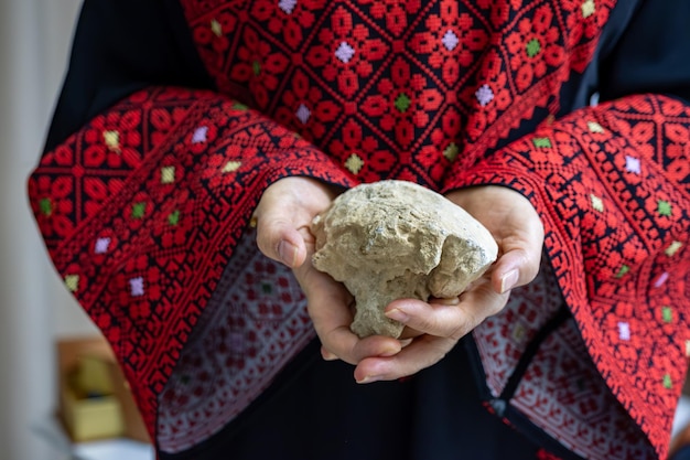 A Palestinian woman holds a stone in her hands which represents the only weapon to resist the occupation