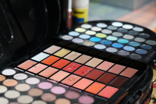 A palette of eyeshadow and a yellow paint can be seen in the background.