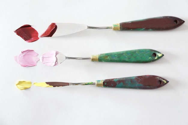 Palette knives with oil paints on white paper