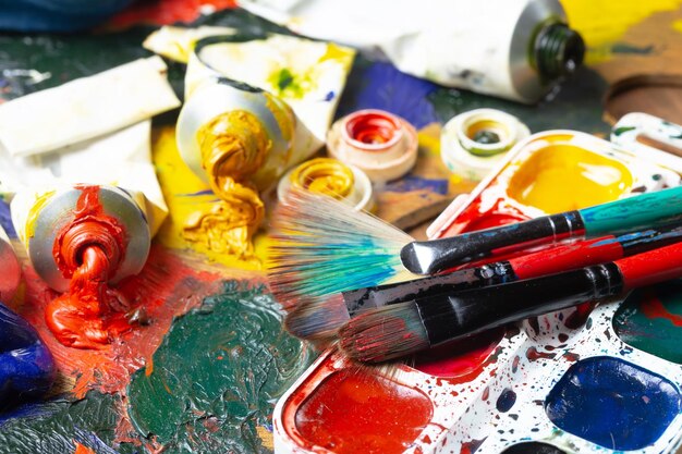 A palette of paint and brushes with a red handle.