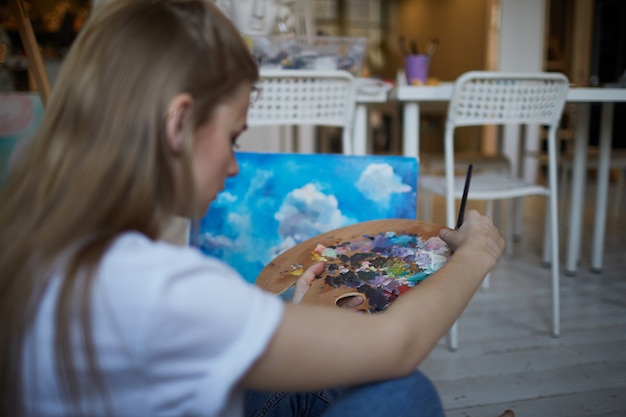 Photo a palette of paints in the hands of a girl.