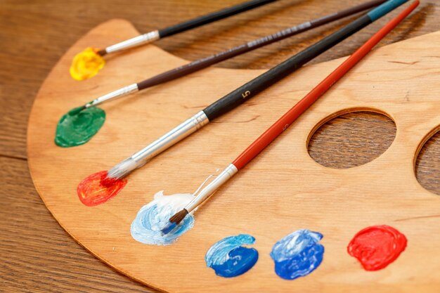 Palette with paints and paintbrushes on the table