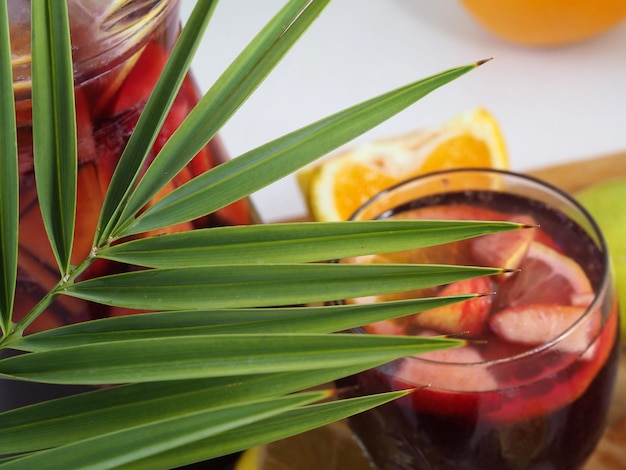 Palm branch against the background of glasses with soft drinks and fruits