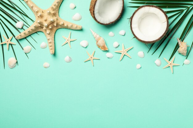 Palm branches, starfishes and coconut on mint, space for text