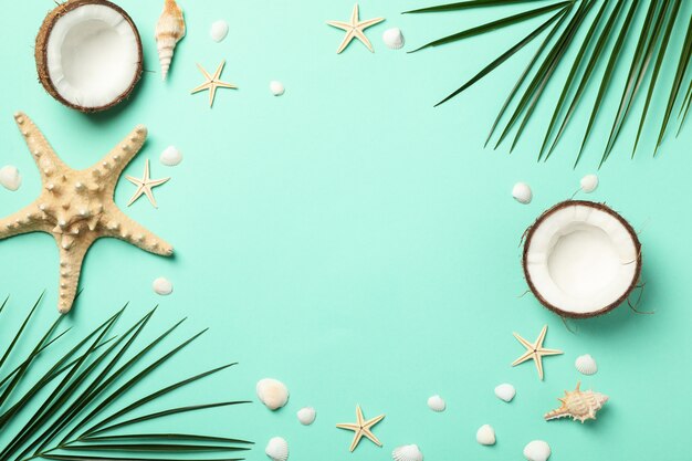 Palm branches, starfishes and coconut on mint, space for text