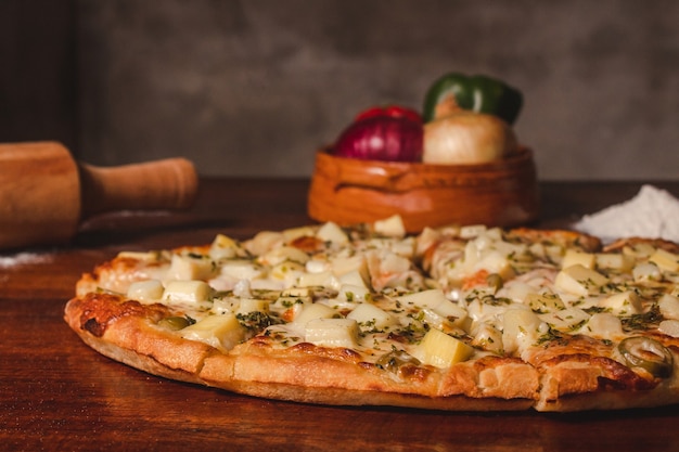 A palm heart pizza cut into pieces is placed next to the ingredients on a wooden table.