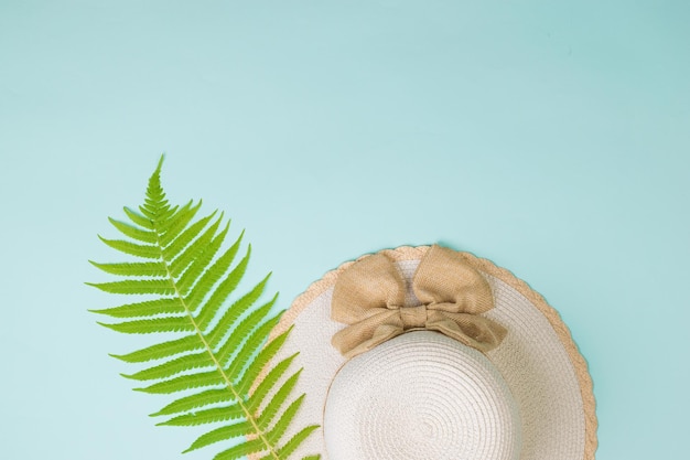 A palm leaf next to a sun hat on a blue background The view from the top