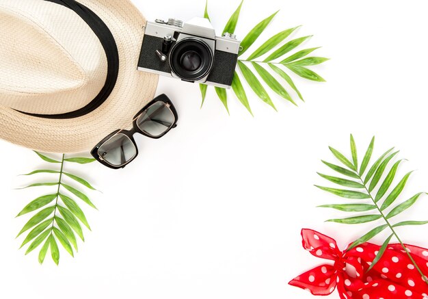 Palm leaves, sunglasses, photo camera, summer hat. Floral flat lay