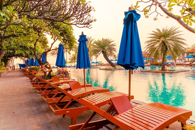 palm tree with umbrella chair pool in luxury hotel resort at sunrise times