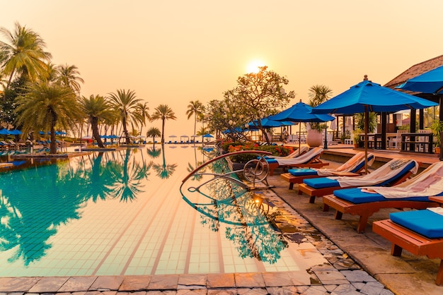 palm tree with umbrella chair pool in luxury hotel resort at sunrise times