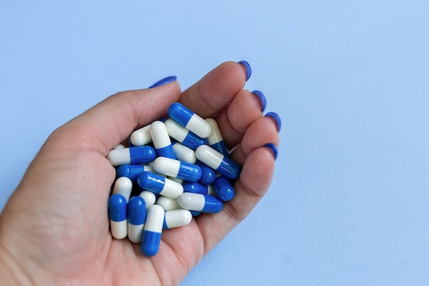 手のひらには青と白の一握りの薬のカプセルがあります。