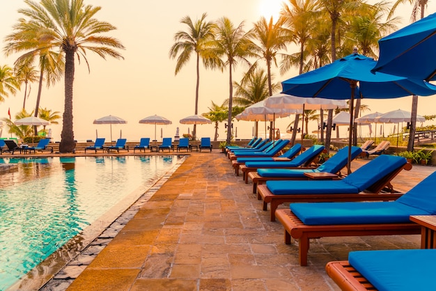 palmboom met parasolstoel zwembad in luxe hotelresort bij zonsopgang