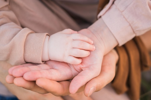 The palms of dad and mom that hold the handle of a newborn baby