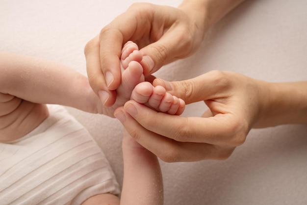 The palms of the father, the mother are holding the foot of the newborn baby. Feet of the newborn on the palms of the parents. Studio photography of a child's toes, heels and feet. Concept.