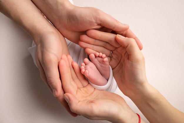 The palms of the father the mother are holding the foot of the newborn baby Feet of the newborn on the palms of the parents Studio photography of a child39s toes heels and feet Concept