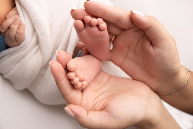 부모의 손바닥 아버지와 어머니는 흰색 배경에 흰색 담요에 신생아의 발을 잡고 부모의 손에 신생아의 발 발 뒤꿈치와 발가락 사진