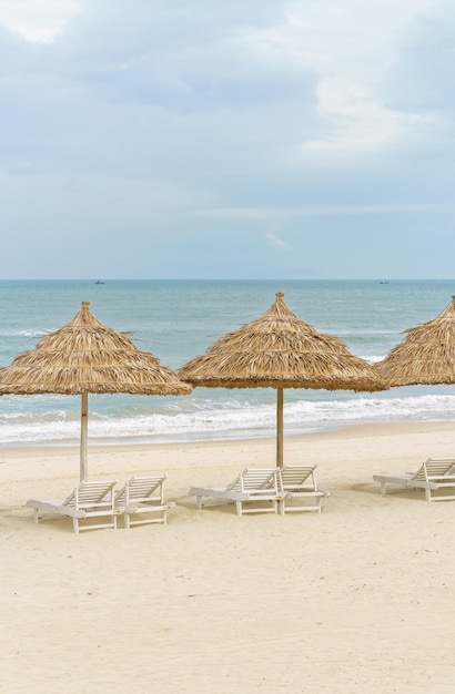 Palmschuilplaats en ligbedden op het China-strand in Da Nang, Vietnam. Het wordt ook Non Nuoc Beach genoemd. Zuid-Chinese Zee op de achtergrond.